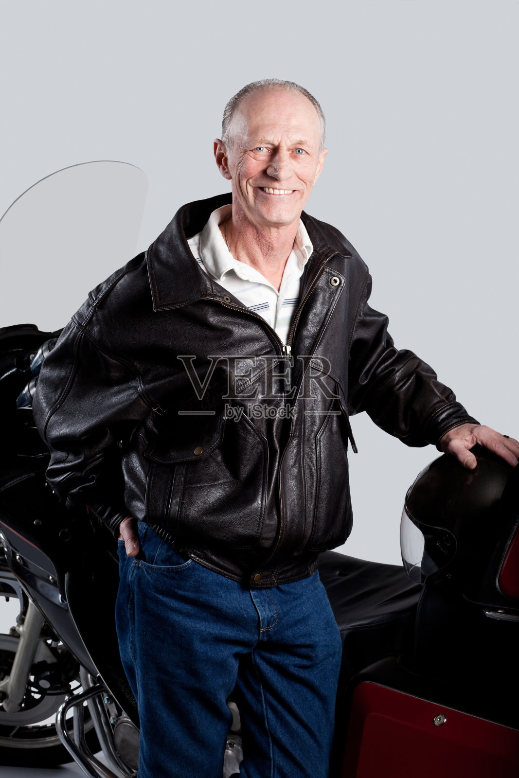 摄影棚里一个骑摩托车的老人。照片摄影图片