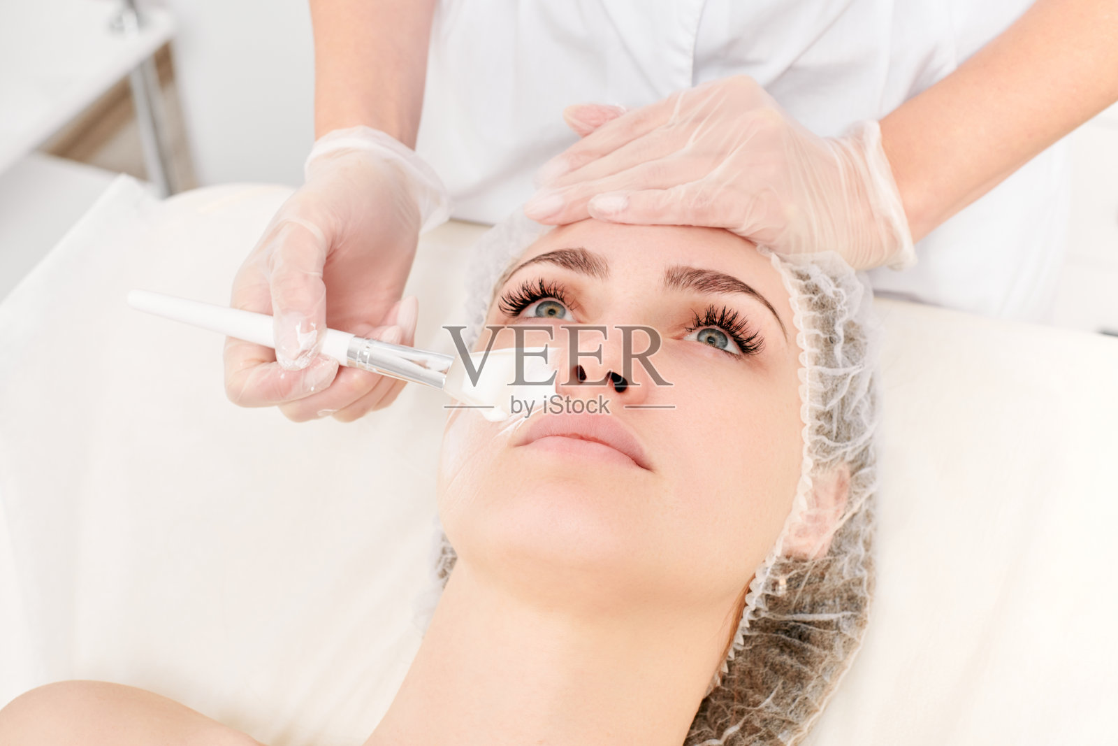 美容师将奶油面膜敷在女士的脸上，使面部皮肤恢复活力，这是美容院的程序照片摄影图片