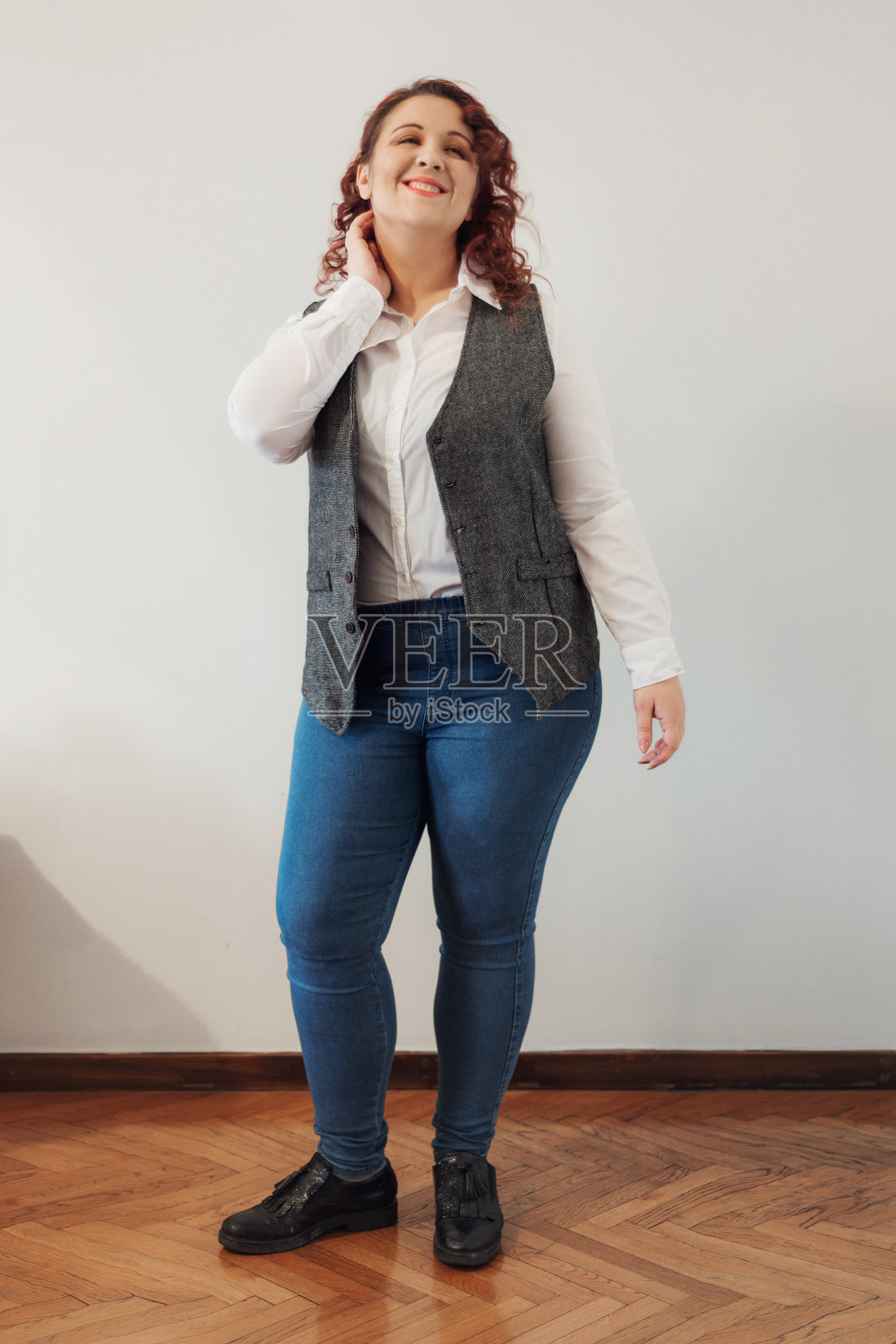 年轻的红发和美丽的女人摆着微笑，眼睛闭着，全长肖像照片摄影图片