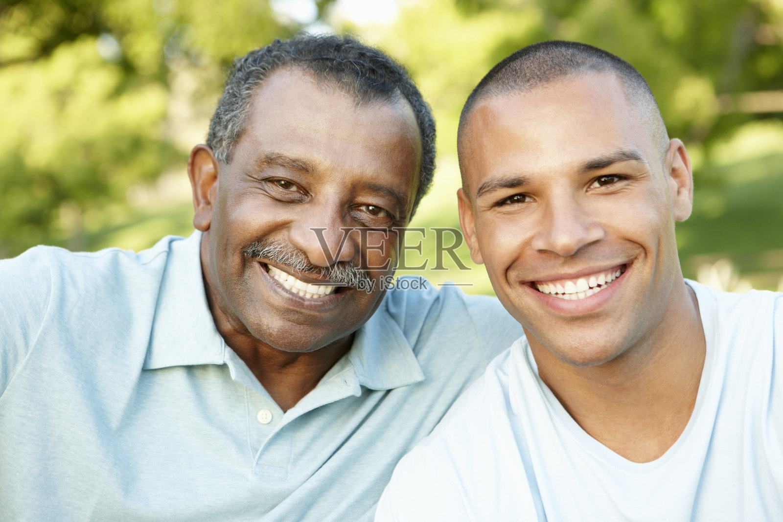 非裔美国父亲和成年的儿子在公园里放松照片摄影图片