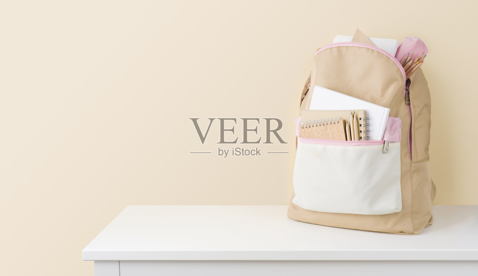 时髦的背包与学校文具在桌子上对米色背景照片摄影图片