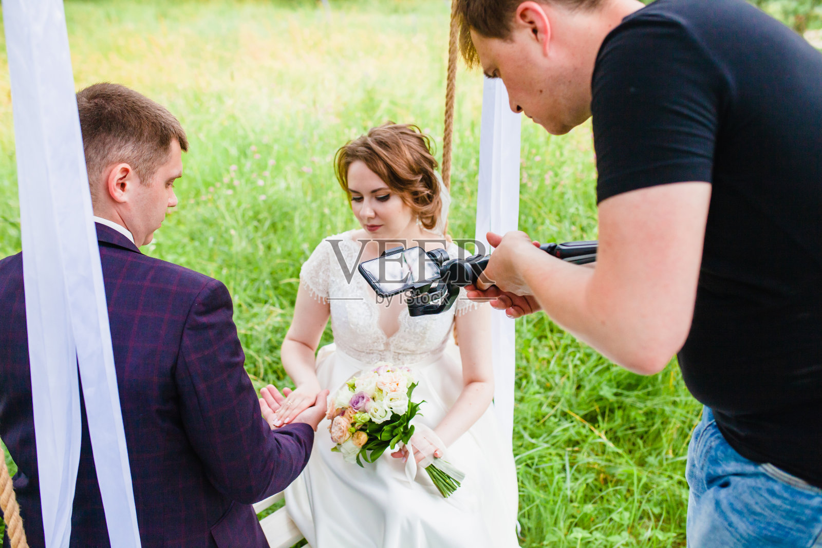 摄像师在松林中拍摄这对新婚夫妇在秋千上的镜头照片摄影图片