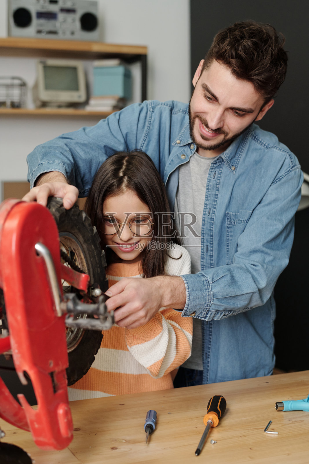 年轻男子在车库里教小女儿如何修理自行车轮照片摄影图片