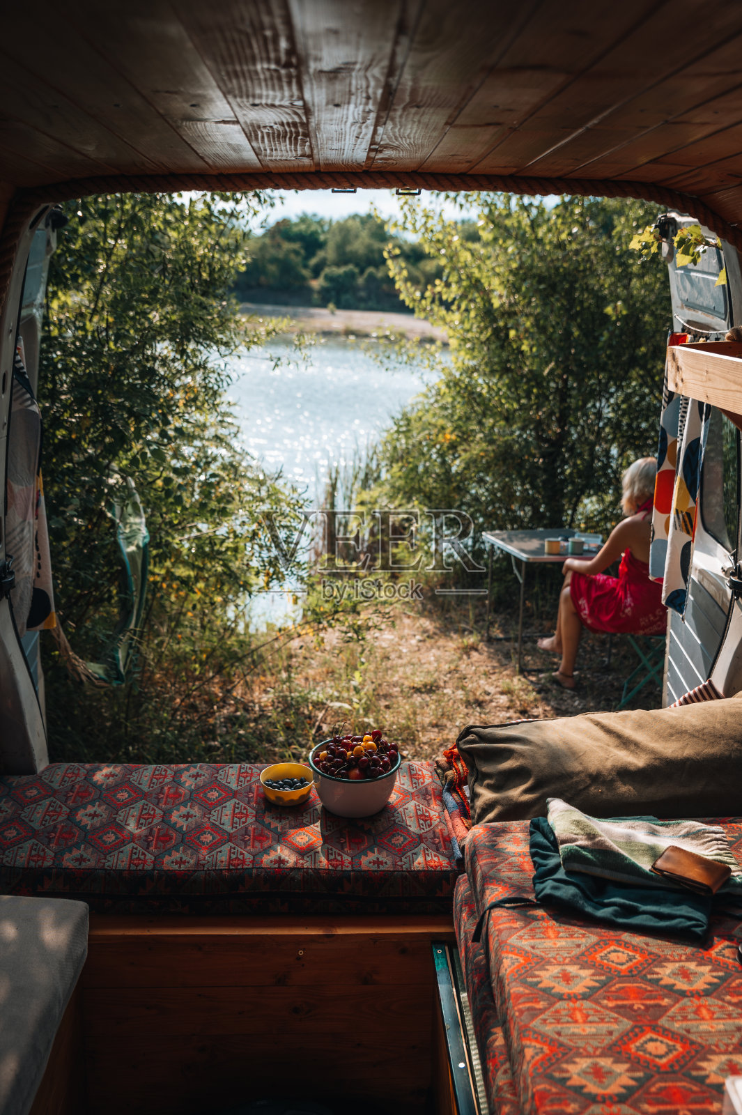 从露营车上看到一位年轻女子坐在湖前放松照片摄影图片