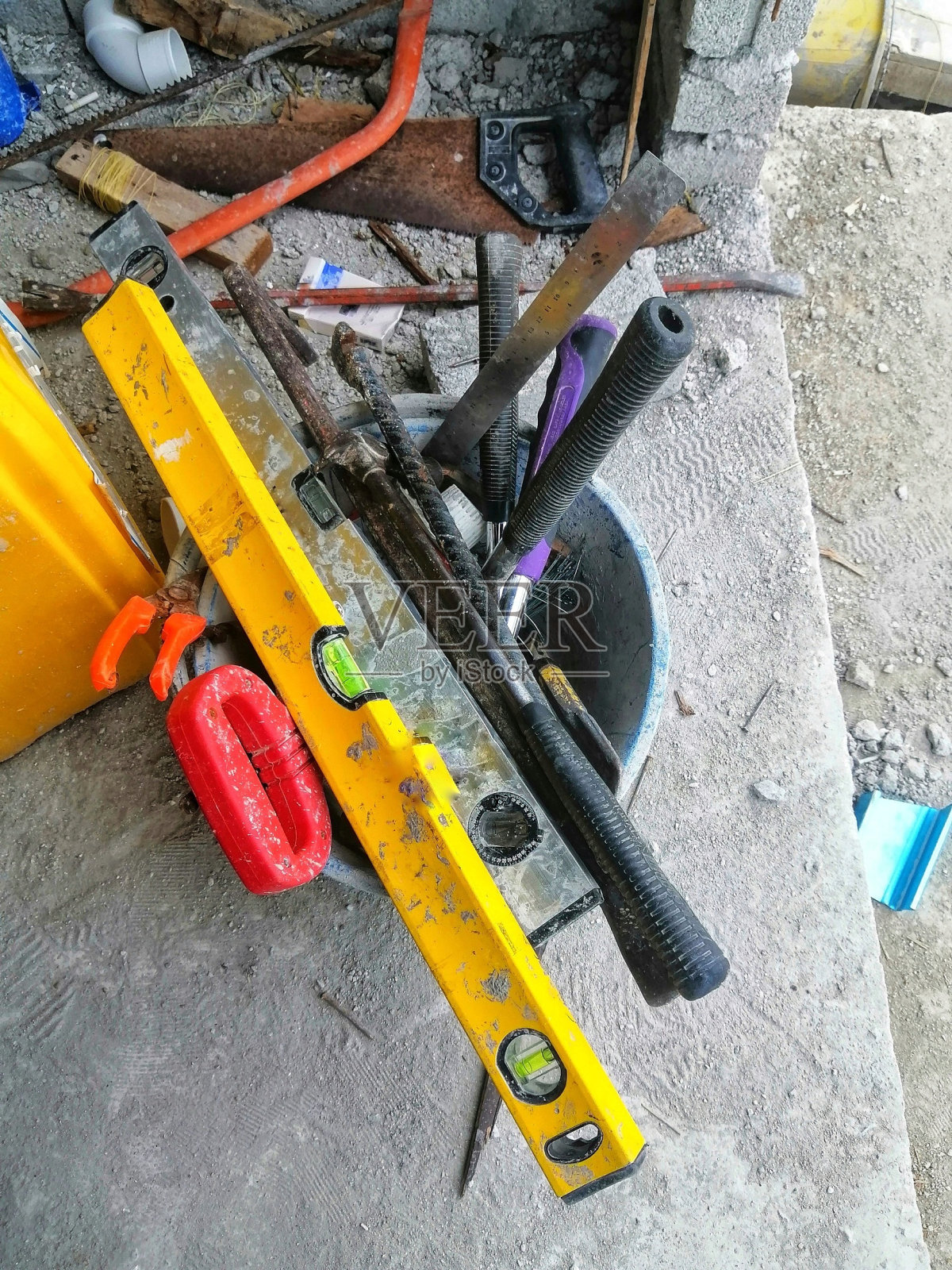 一堆建筑工具在现场的一个桶里。建造房屋的重要工具。照片摄影图片