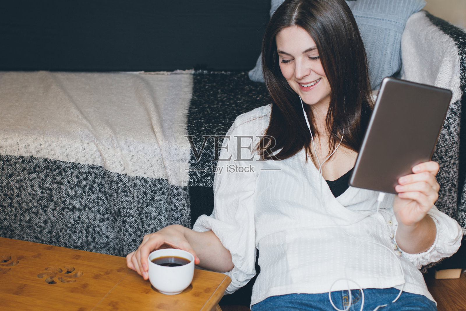 年轻女子在家边视频聊天边喝咖啡。照片摄影图片