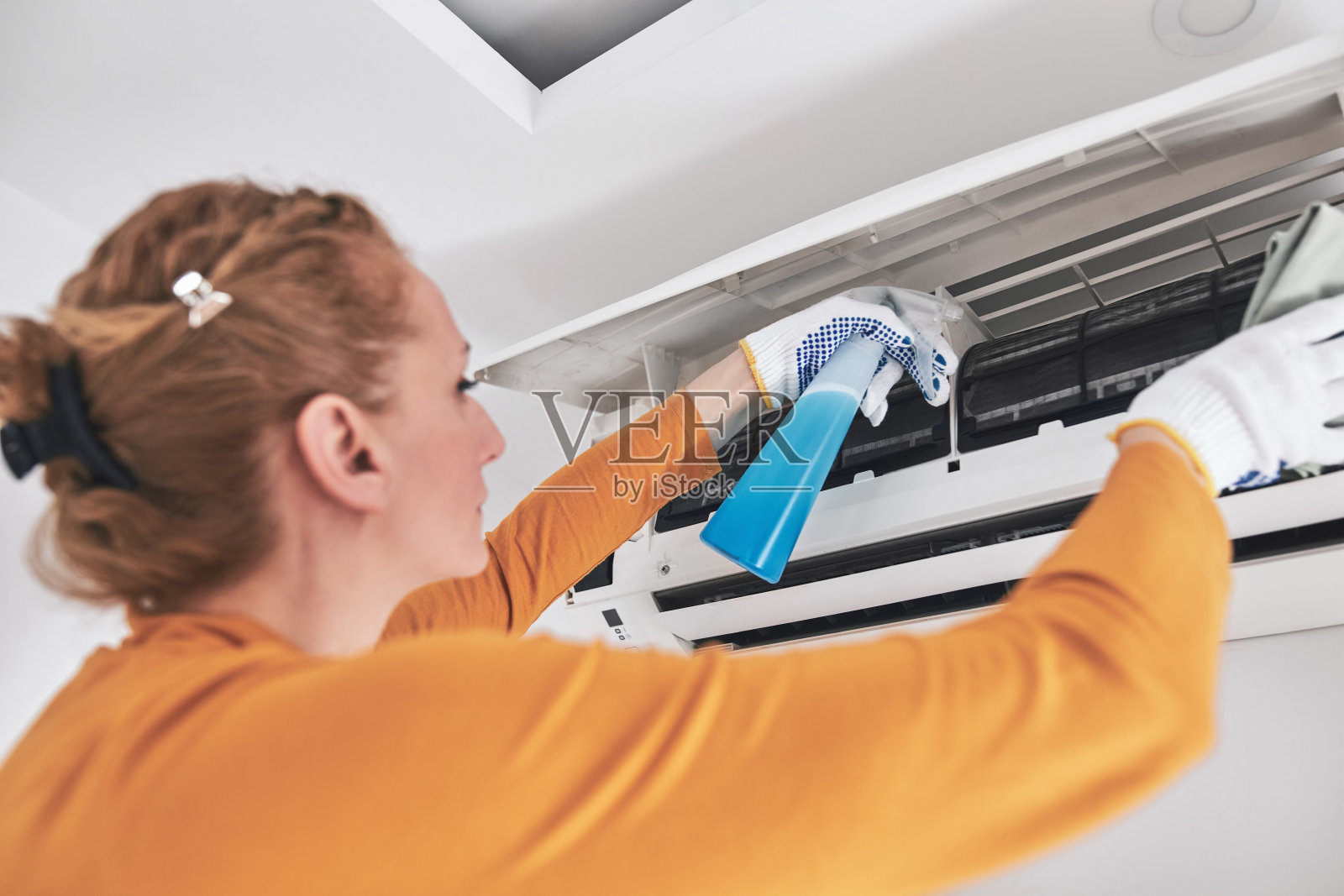妇女清洁空调过滤器室内单位在家里。照片摄影图片