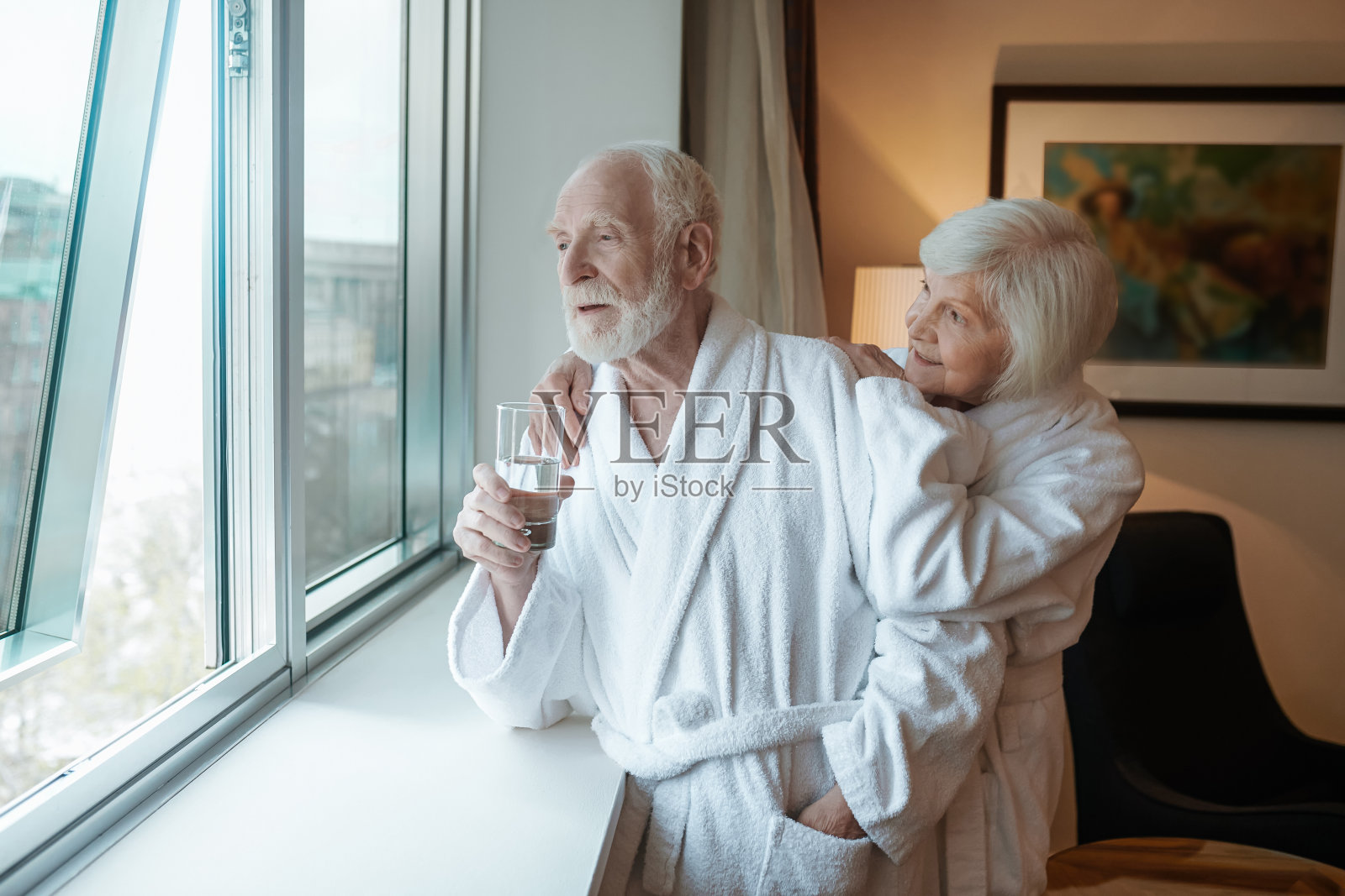 一对幸福的老夫妇站在旅馆的窗边照片摄影图片