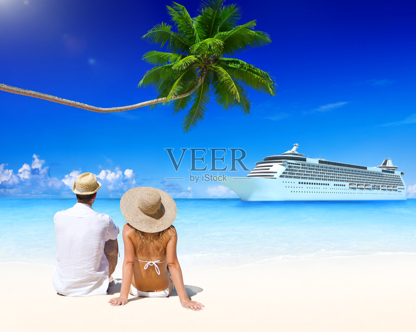 一对夫妇在热带海滩上，水上有一艘游船照片摄影图片