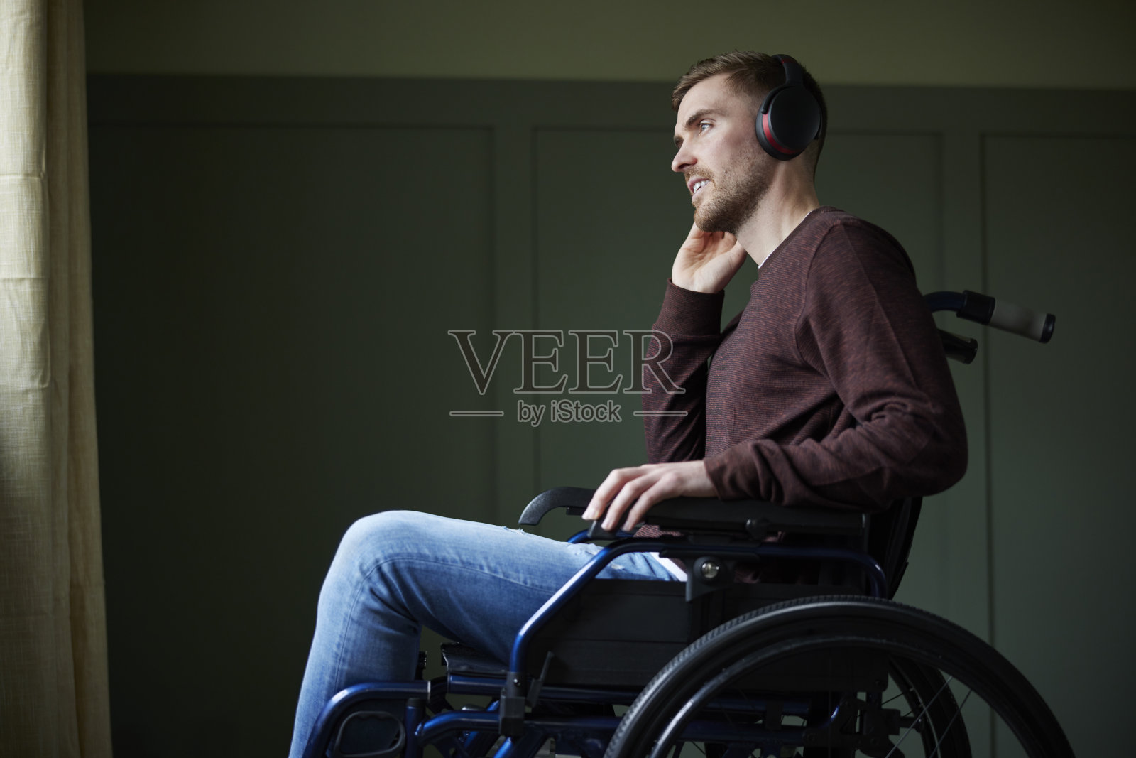 坐在轮椅上的人在家用无线耳机听音乐或播客照片摄影图片