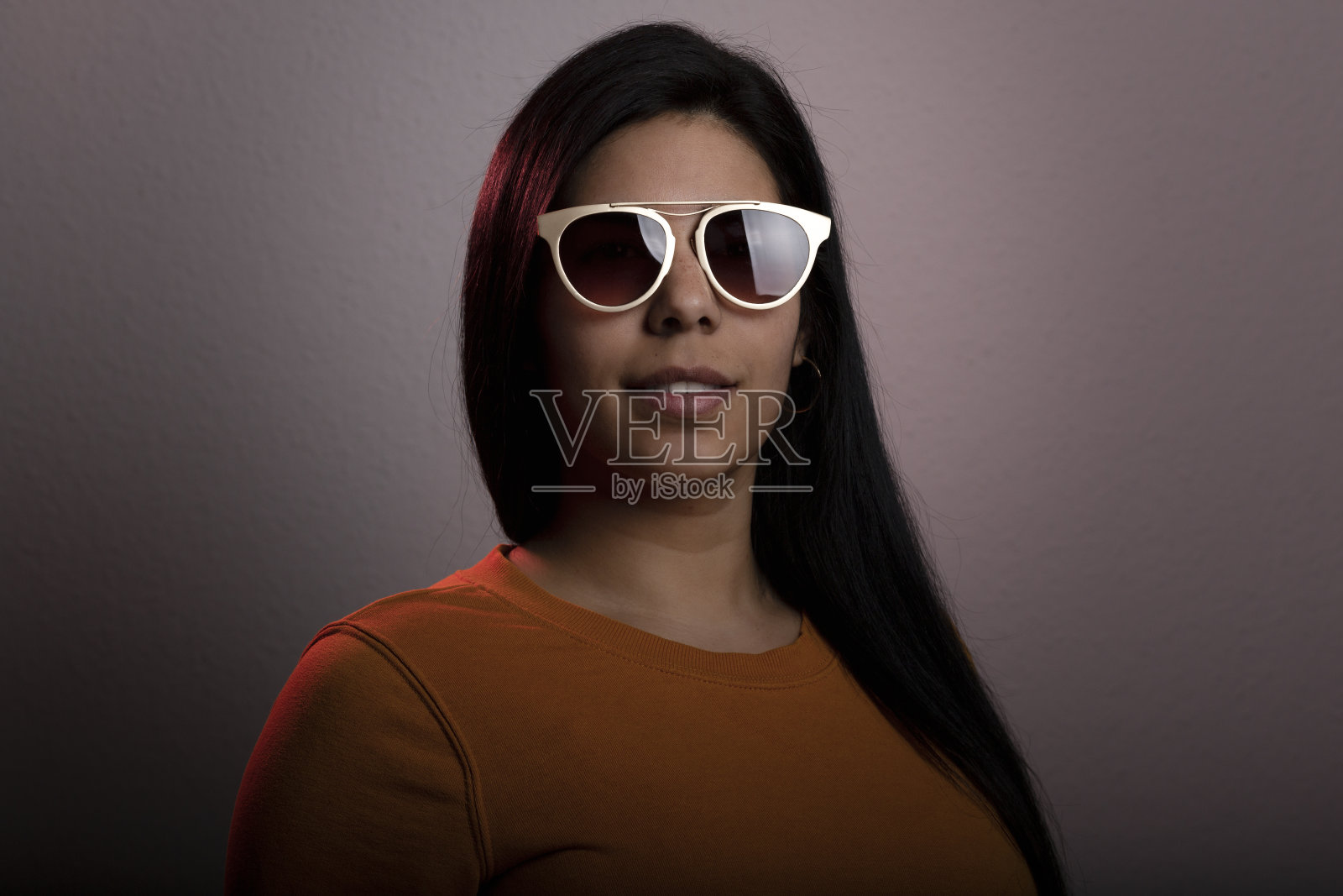 年轻的拉丁女人工作室肖像。她很严肃，戴着墨镜望着镜头。照片摄影图片