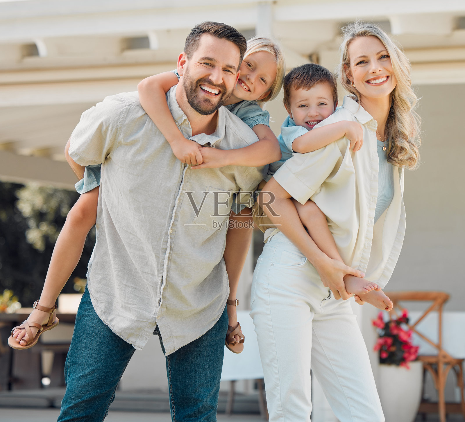 快乐的父母给他们的小孩骑在花园里的肖像。微笑的白人夫妇和他们可爱的儿子和女儿在后院。顽皮的孩子享受照片摄影图片