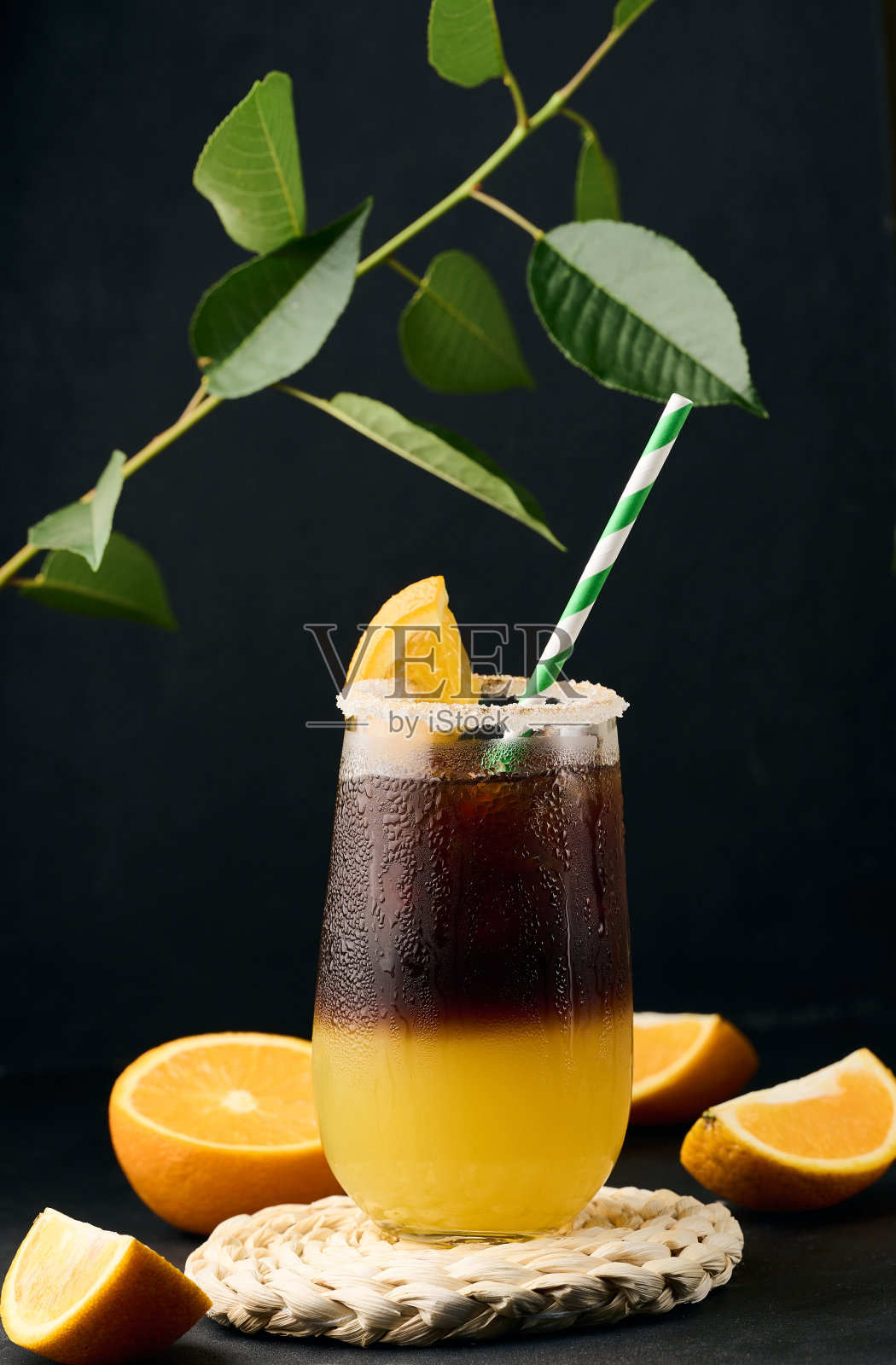 透明玻璃杯里的冰咖啡加橙汁，桌上放着清爽的小杯咖啡，黑色背景照片摄影图片