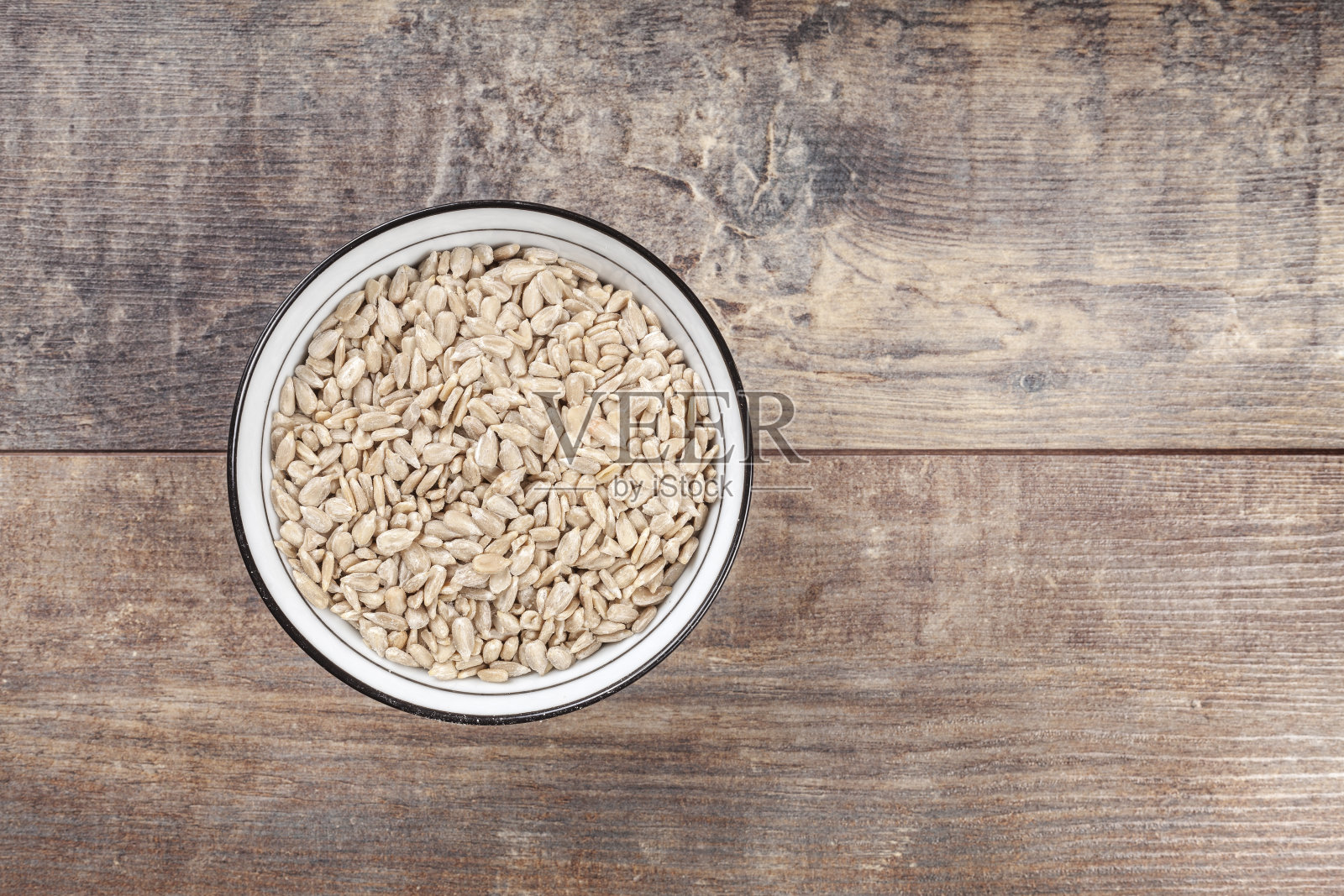 新鲜的葵花籽在一个碗，在木背景照片摄影图片