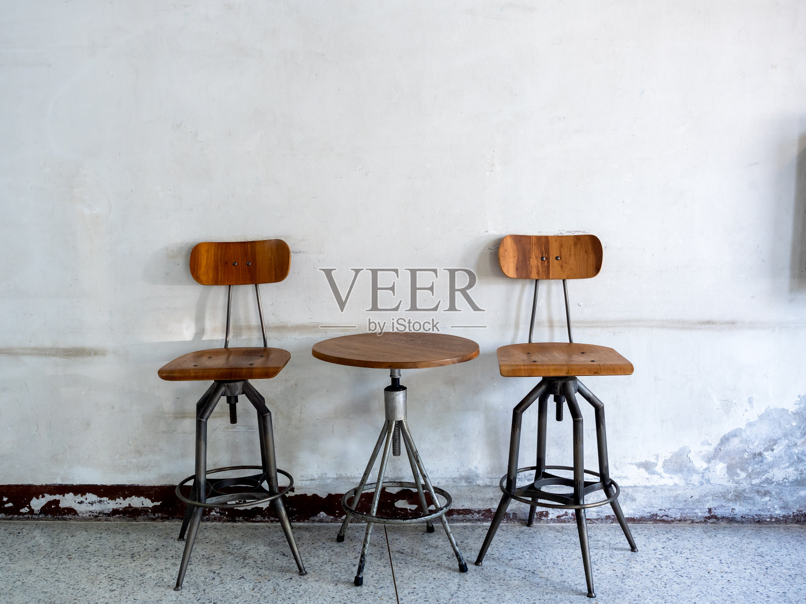 空的复古纺纱椅靠背，座位和圆形纺纱边桌装饰在旧白墙背景，阁楼风格的建筑内部。旋转木桌套，木质和黑铁材质。照片摄影图片