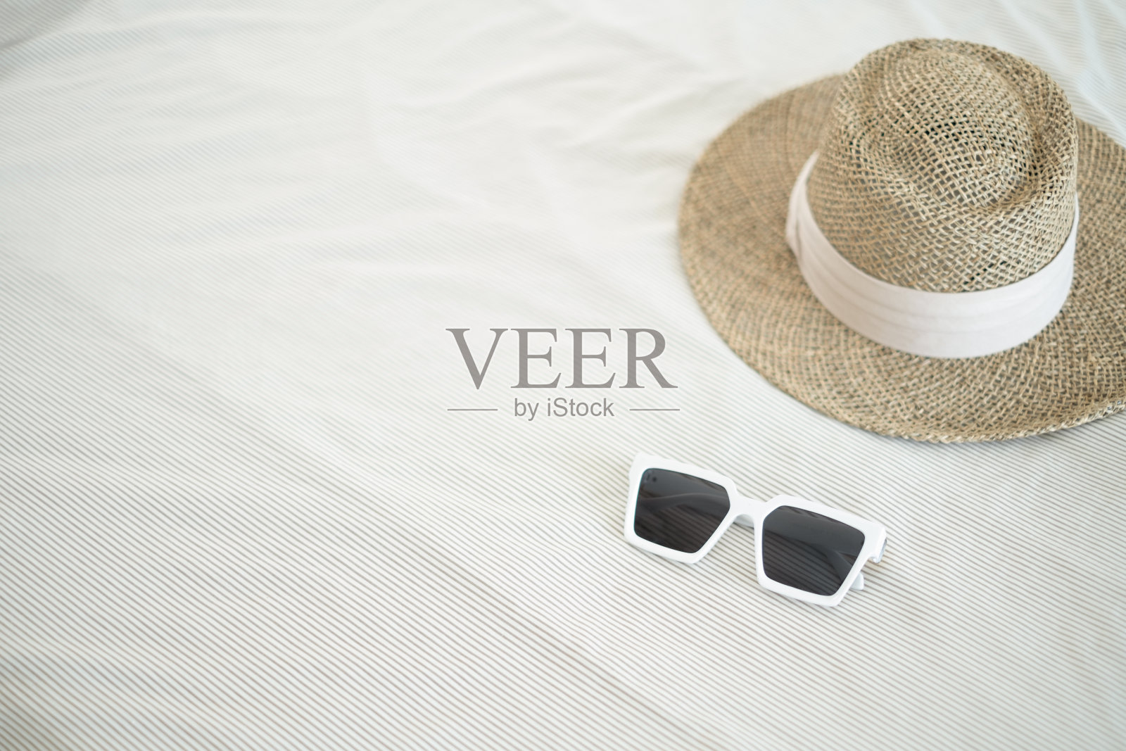 床上放着空的白杯子和棕色草帽。节日的概念照片摄影图片