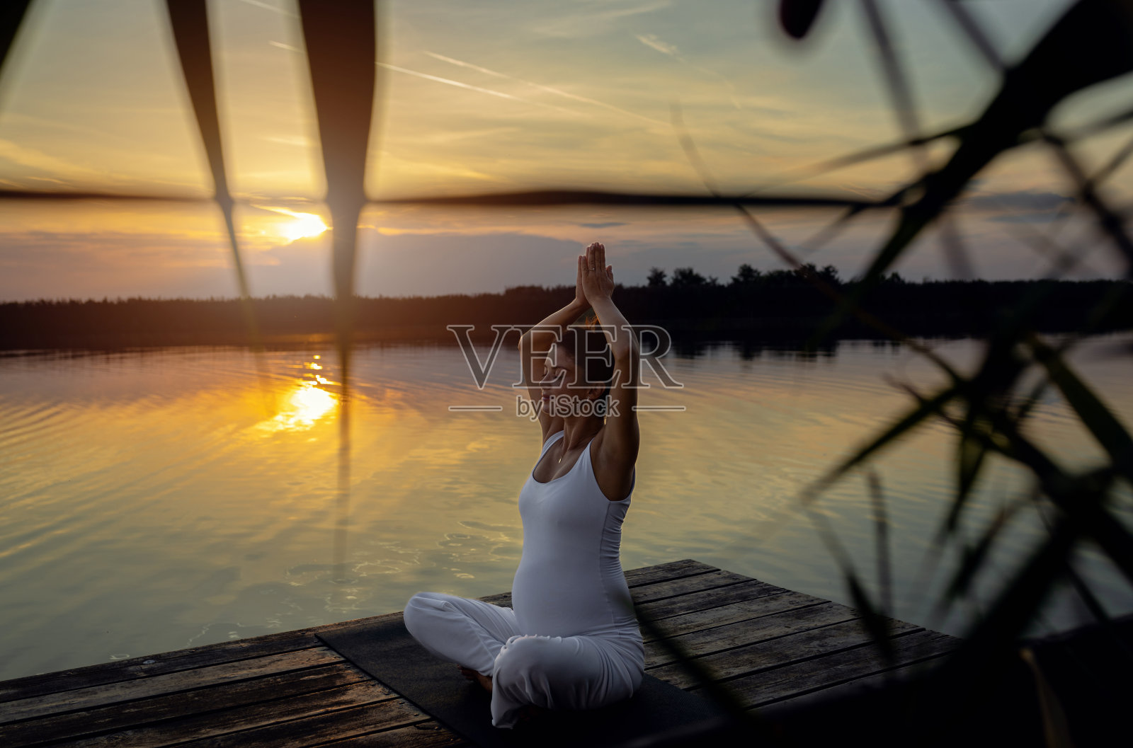 孕妇在日落时分在湖边做瑜伽。照片摄影图片