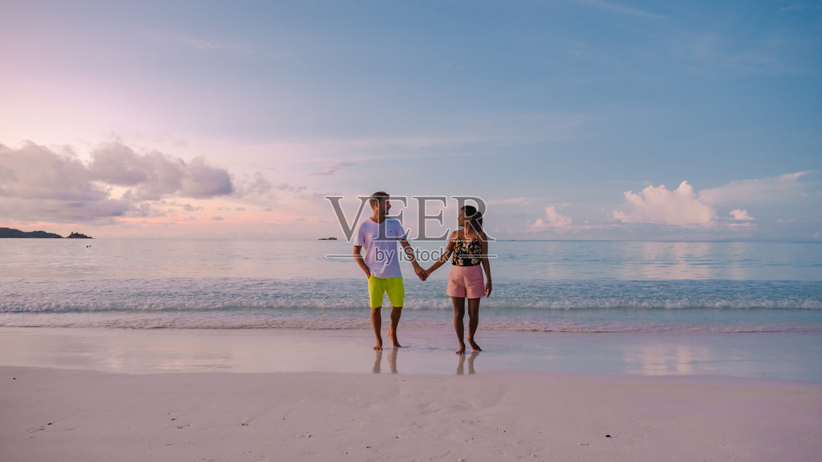 塞舌尔群岛的普拉林热带岛屿，有沙滩和棕榈树，一对中年男女在塞舌尔度假，在大海上看日落照片摄影图片