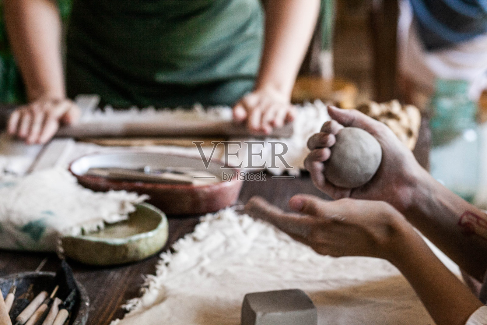 在自然光线下，双手在桌子上雕刻和滚动粘土照片摄影图片
