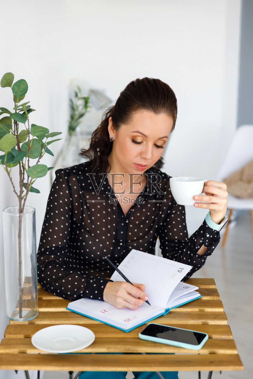 美丽的女人肖像在黑色衬衫，与杯子。布鲁妮特手里拿着白色的杯子，喝着咖啡或茶。女性在商业照片摄影图片