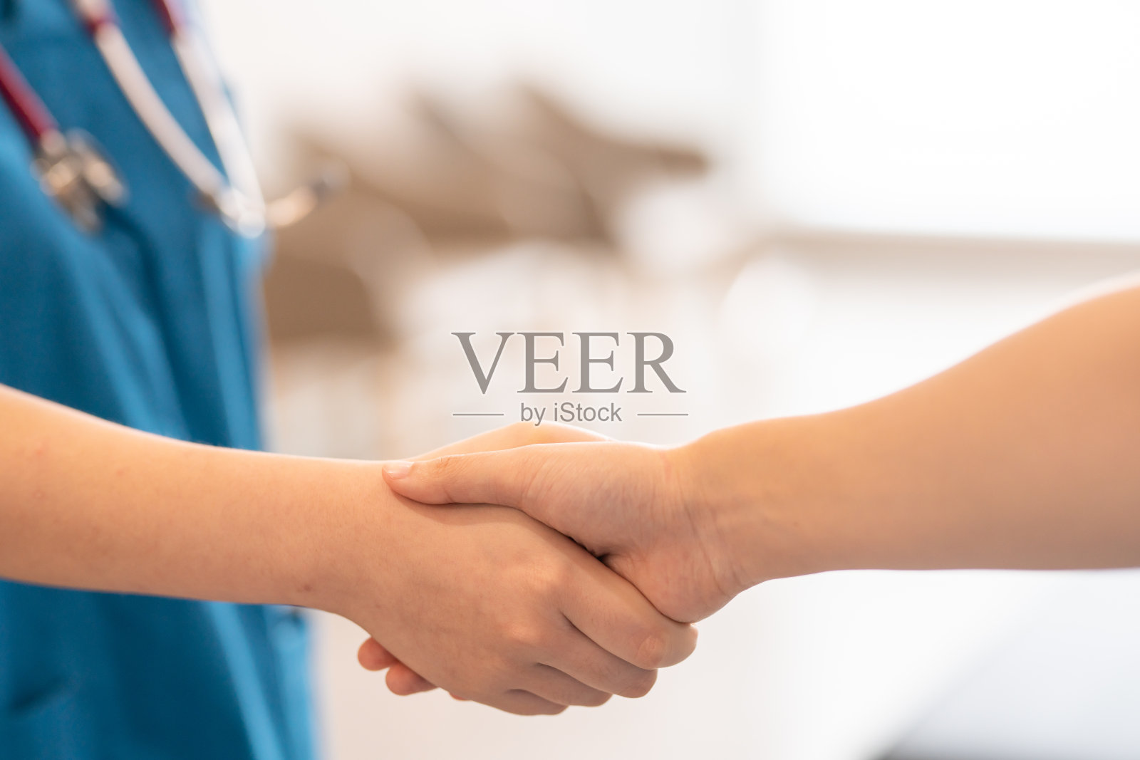 无法辨认的医生在低角度与病人握手。照片摄影图片