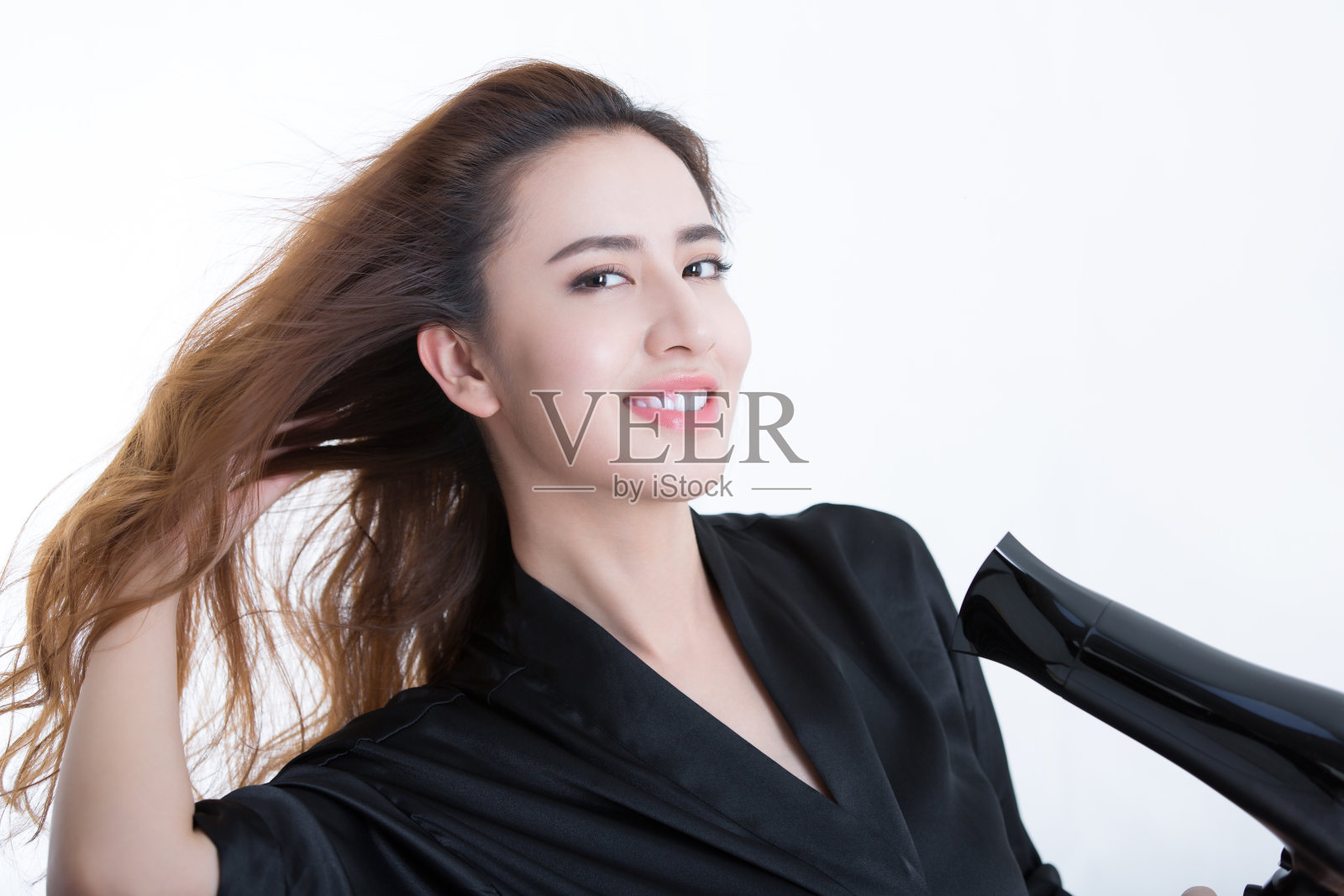 年轻美丽的中国女人用吹风机吹干头发，在白色背景- stock照片照片摄影图片