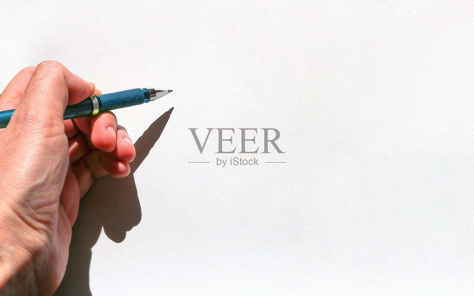 左手少年拿着一支蓝墨水笔，一张白纸——空白的表面上有纹理和手的影子照片摄影图片