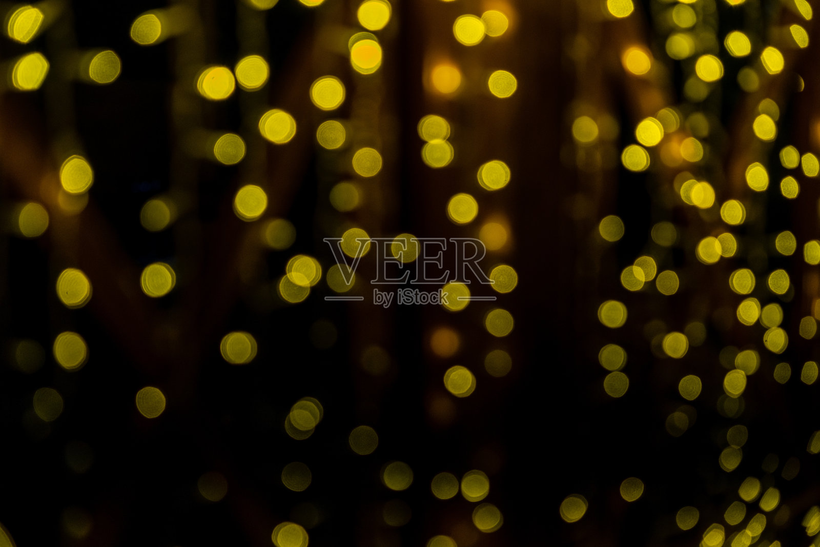 黑色背景上黄色灯光的抽象散景效果。圣诞灯照片摄影图片