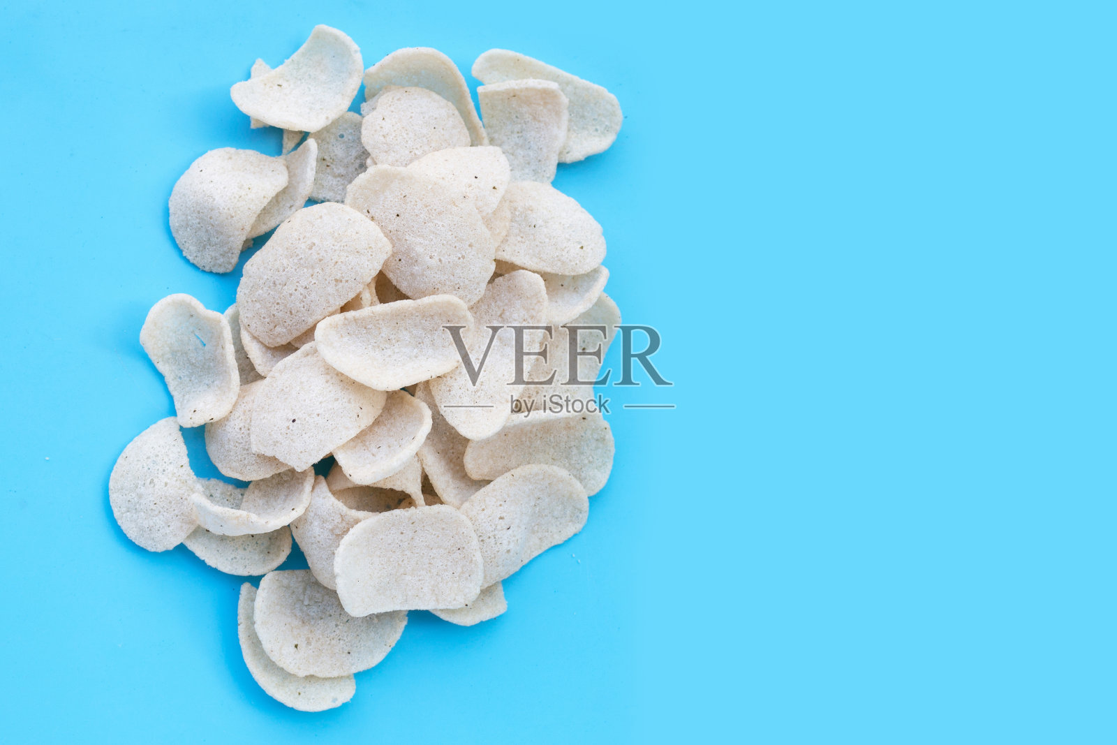 蓝色背景上的虾片。虾仁脆米小吃照片摄影图片