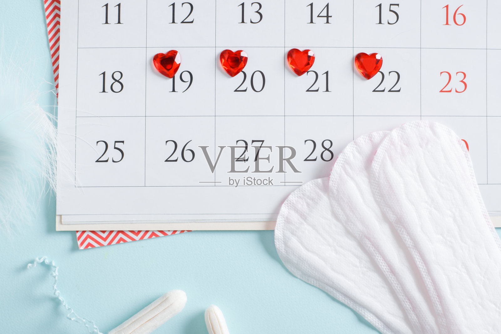 日历的女性月经周期与垫片和卫生棉条在浅蓝色的背景。照片摄影图片