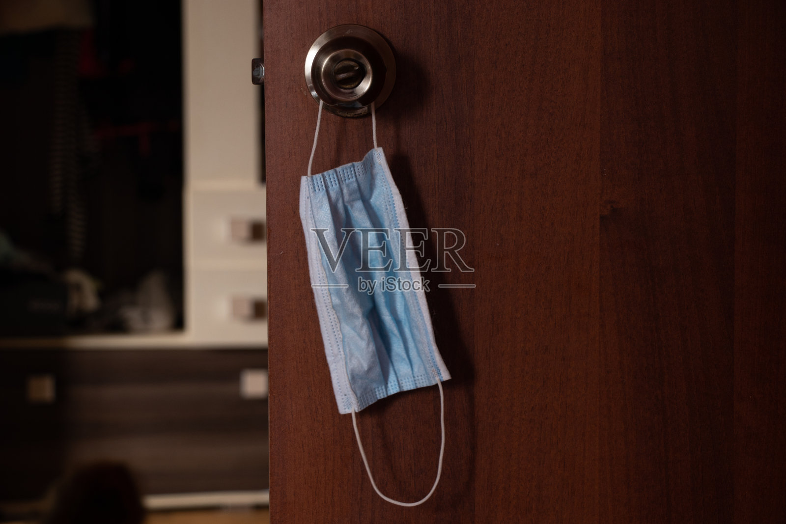 医用口罩挂在房门上的旧暗把手上，进行隔离照片摄影图片