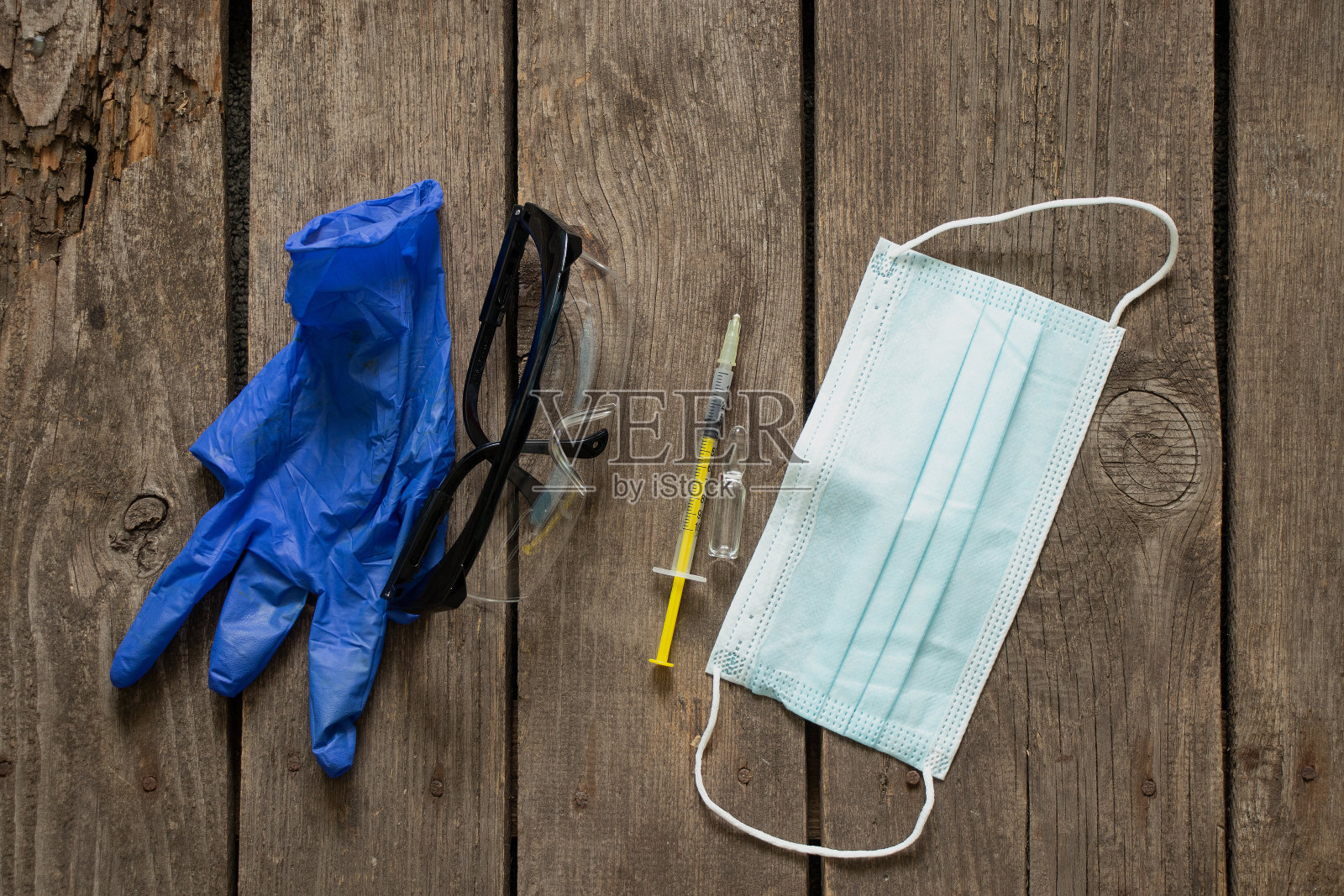 医用口罩、眼镜、注射器、疫苗、安瓿、手套、医生制服躺在木桌上照片摄影图片