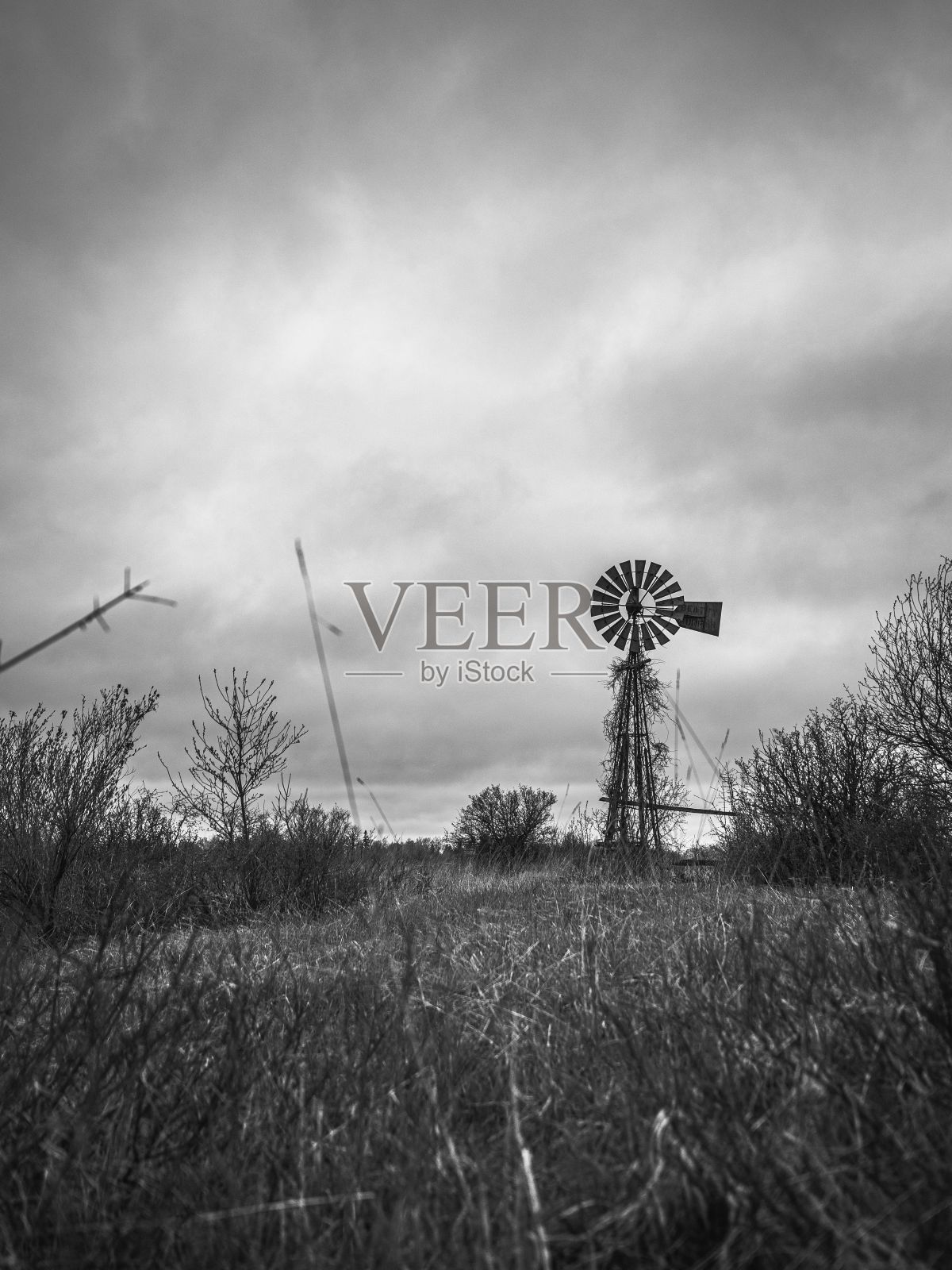 一个废弃的风车的白色图像，天空中有不祥的乌云照片摄影图片