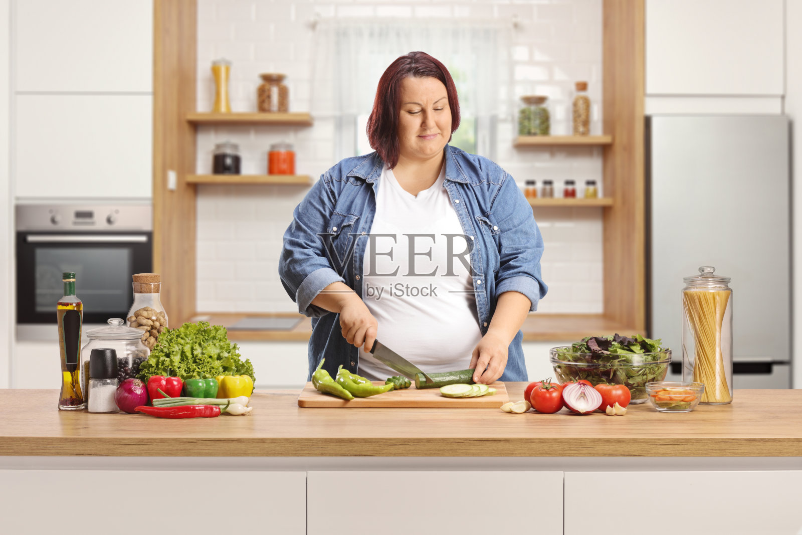 超重的女人在厨房柜台上切蔬菜照片摄影图片