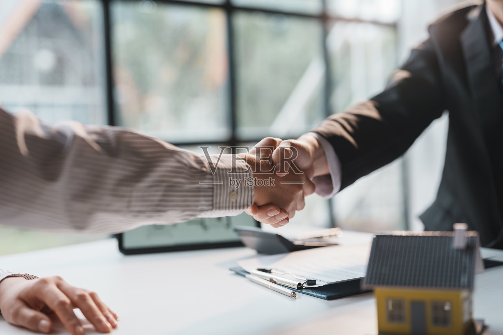 房产中介已签订合同将房屋出售给客户，握手祝贺客户成功拥有房屋。照片摄影图片