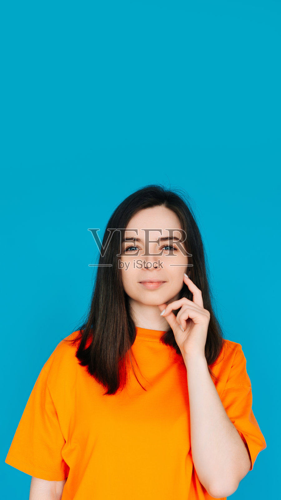 沉思的女人触摸下巴，沉思，复制空间，孤立在蓝色背景。一个美丽的女人抚摸她的下巴，沉思照片摄影图片