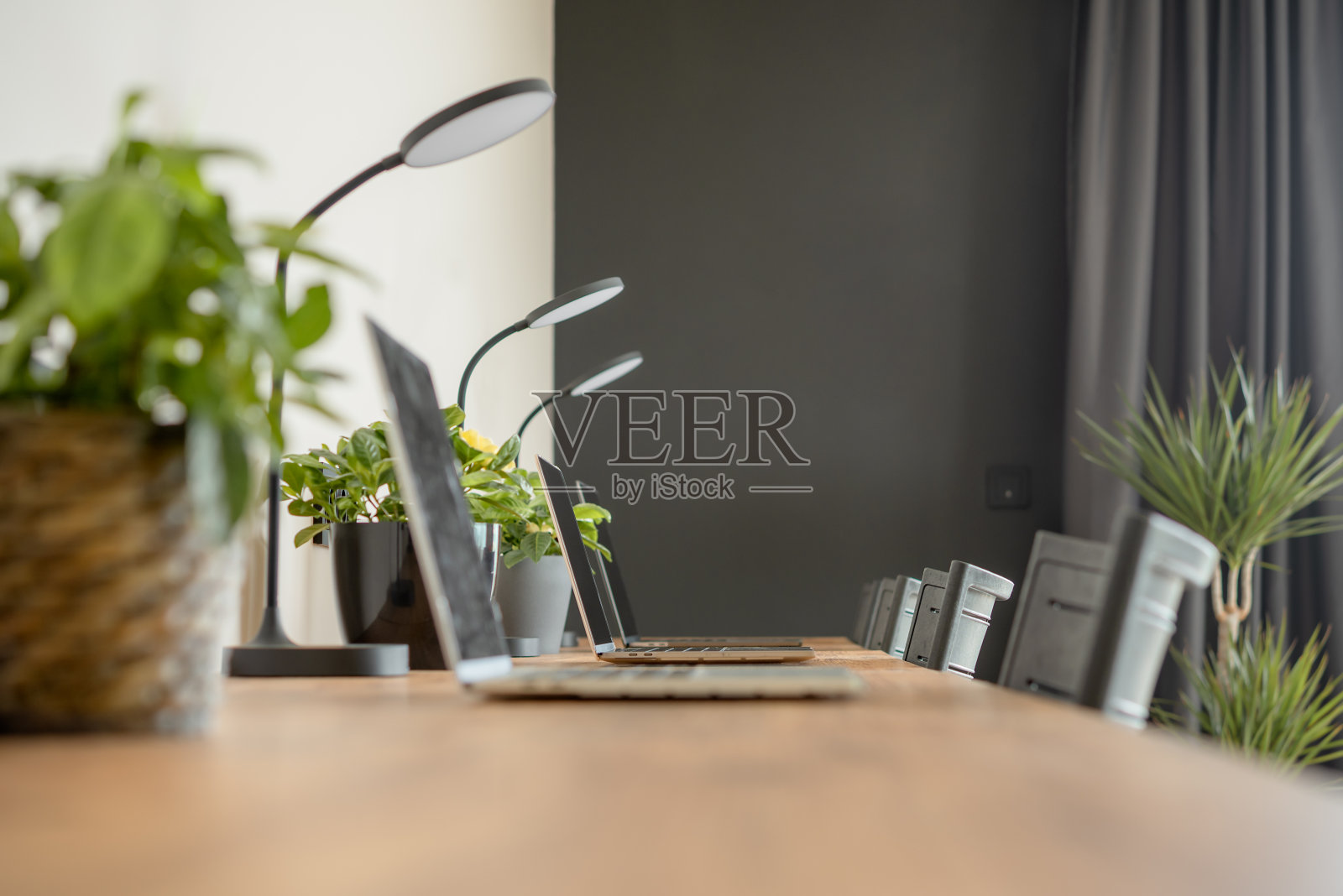 木制桌面和笔记本电脑在一个舒适的现代室内共同工作空间。照片摄影图片