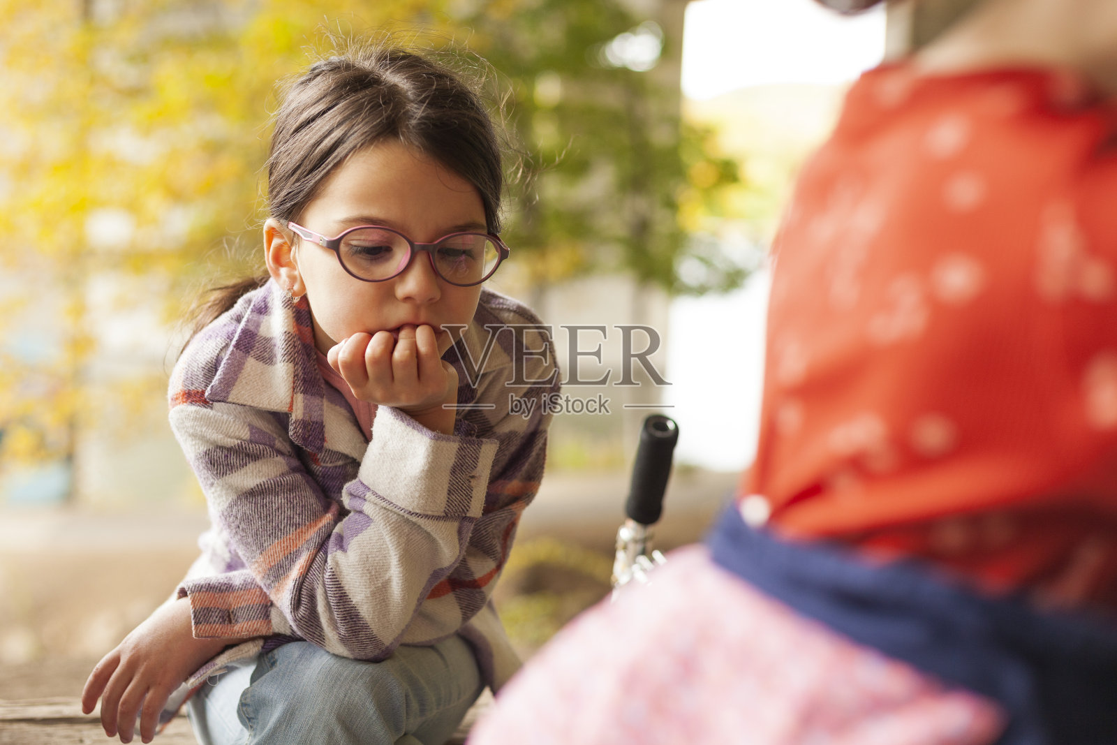 秋天公园里一个戴眼镜的小女孩的画像。照片摄影图片