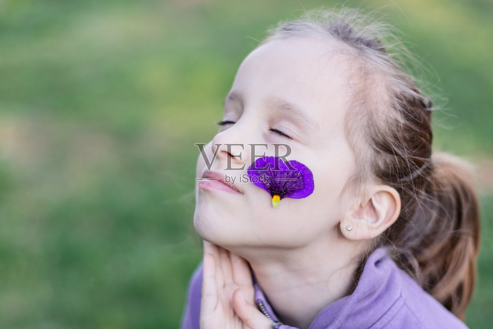 女孩脸上带着紫色的花照片摄影图片