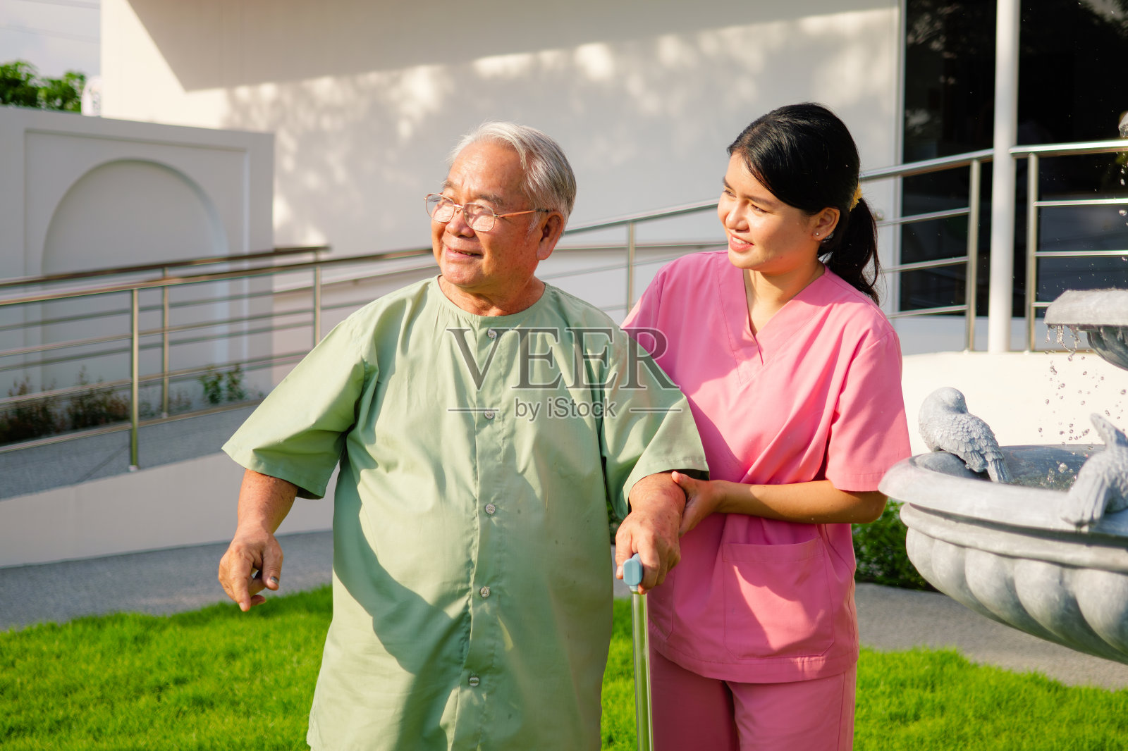护士在医院或疗养院帮助老年人锻炼和散步，年轻女医务人员在养老院帮助老年人，医院或疗养院的卫生保健照片摄影图片