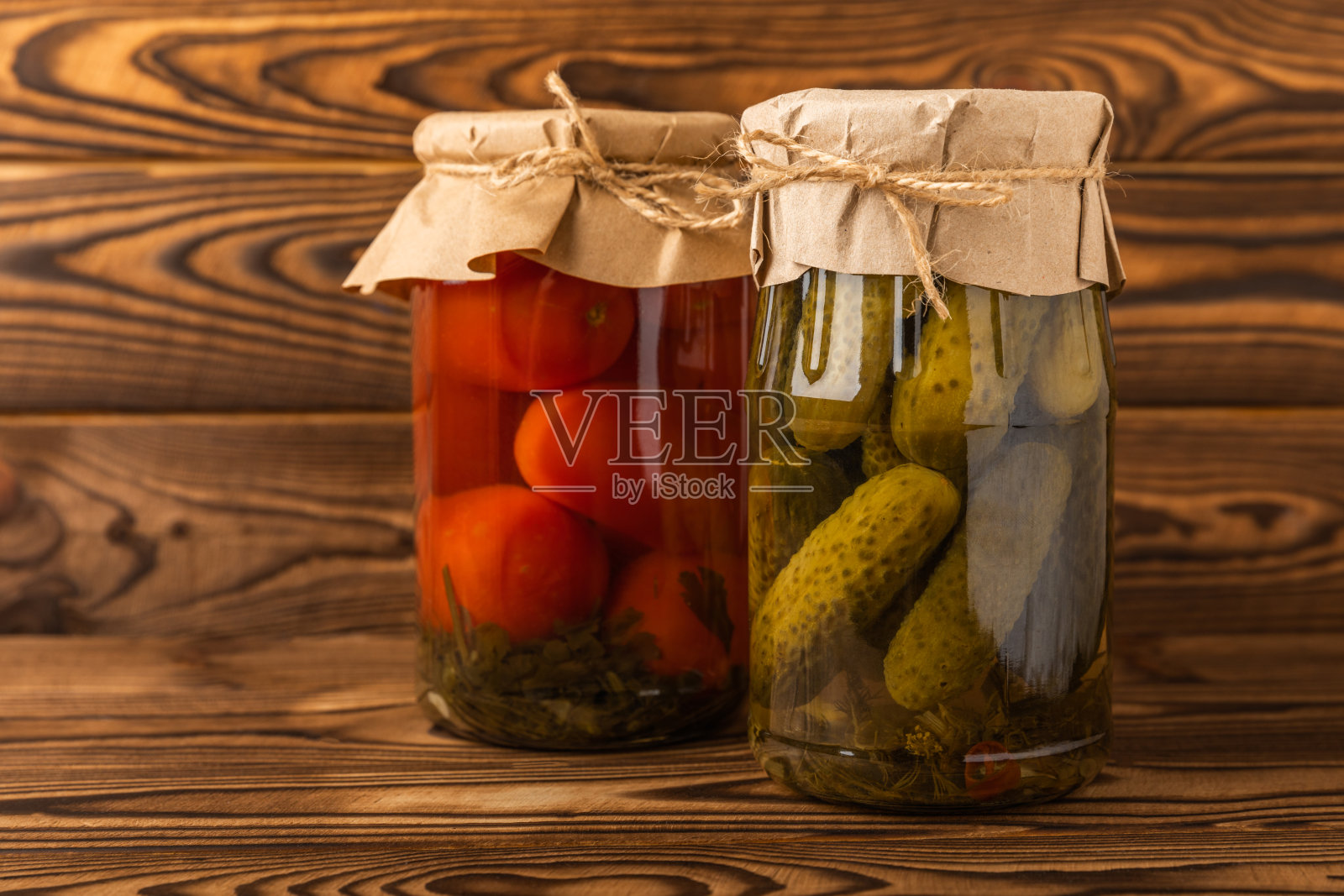 装有泡菜的罐子。腌制的食物。一罐罐的腌菜:在质朴的木制背景上放着黄瓜和西红柿。腌制和罐装食品。照片摄影图片