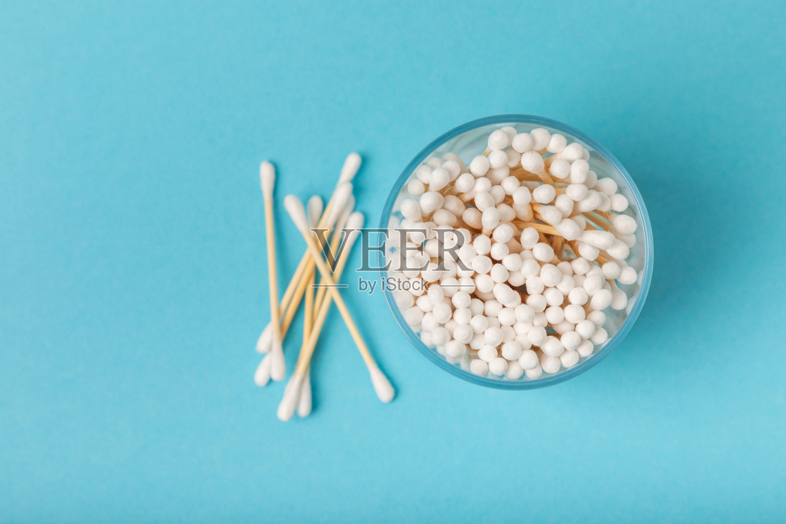 蓝色背景上的棉花芽。环保材料。白色背景上的木制棉签。竹签和棉花。零废弃物，无塑料的生活理念。放文字的地方。照片摄影图片