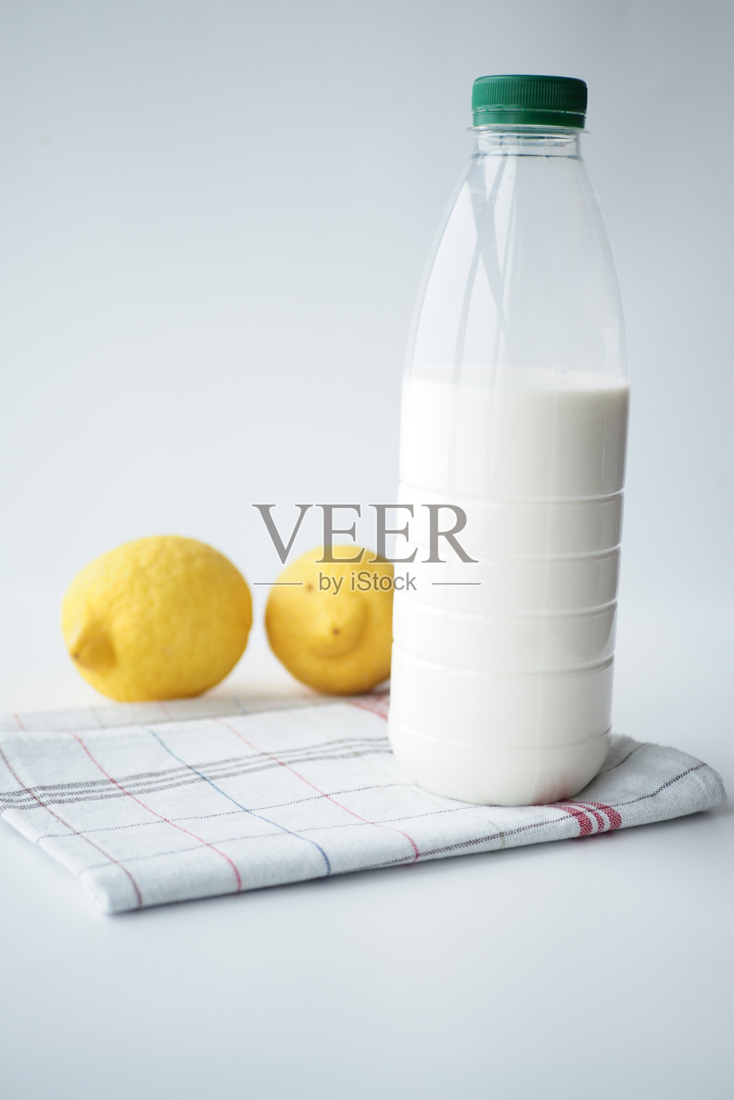 白色背景上的一瓶牛奶和黄色柠檬照片摄影图片