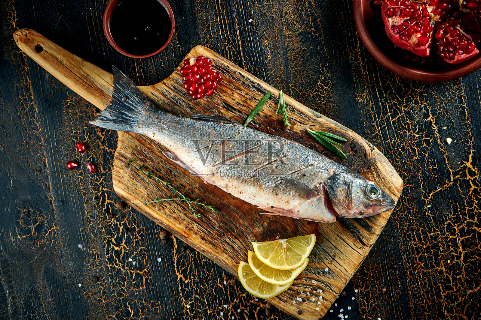 用香料和柠檬在木板上腌制新鲜的海鲈鱼照片摄影图片