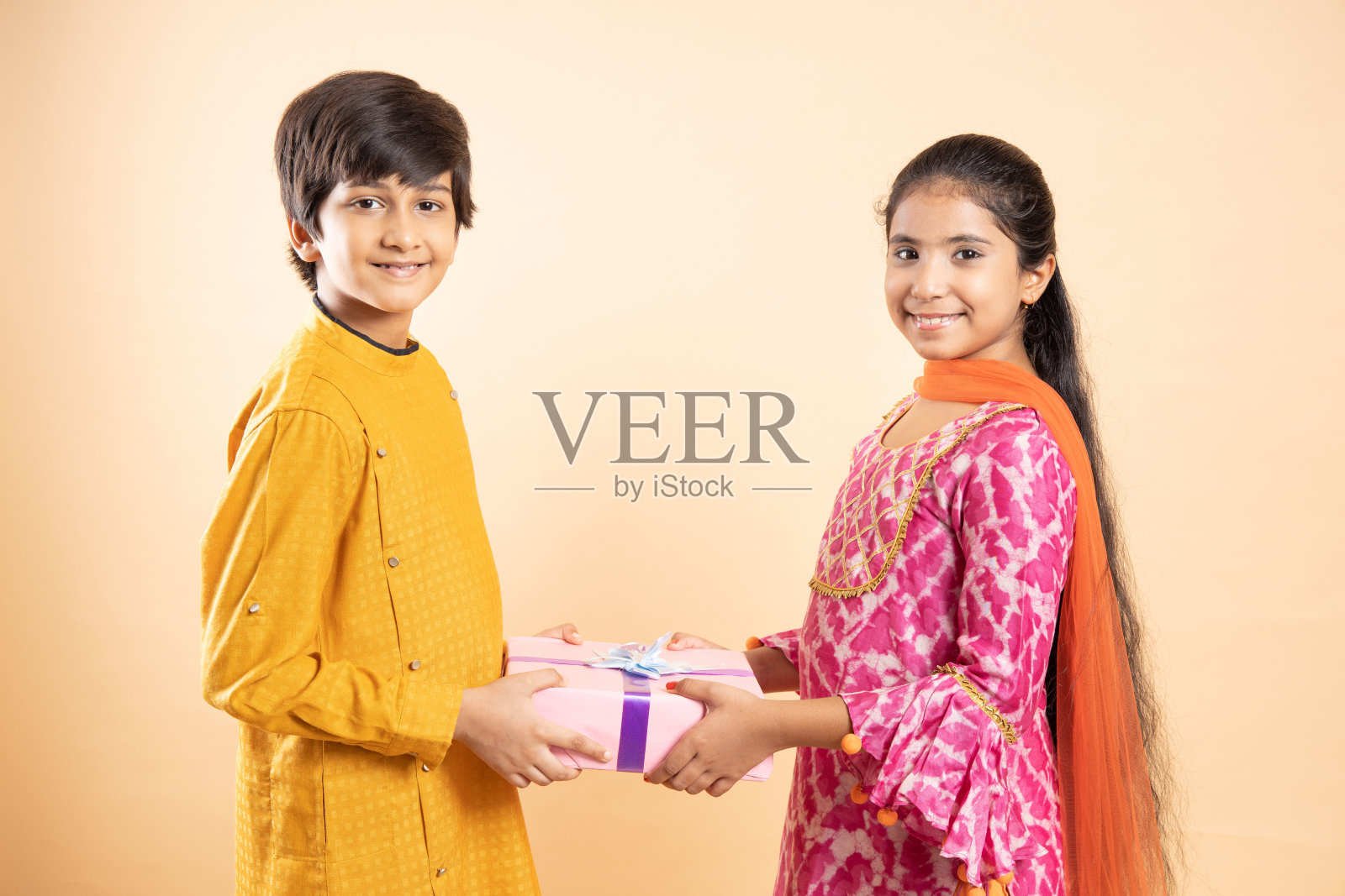 快乐的年轻印度孩子交换礼盒庆祝排灯节一起孤立的工作室背景。哥哥给妹妹礼物。照片摄影图片