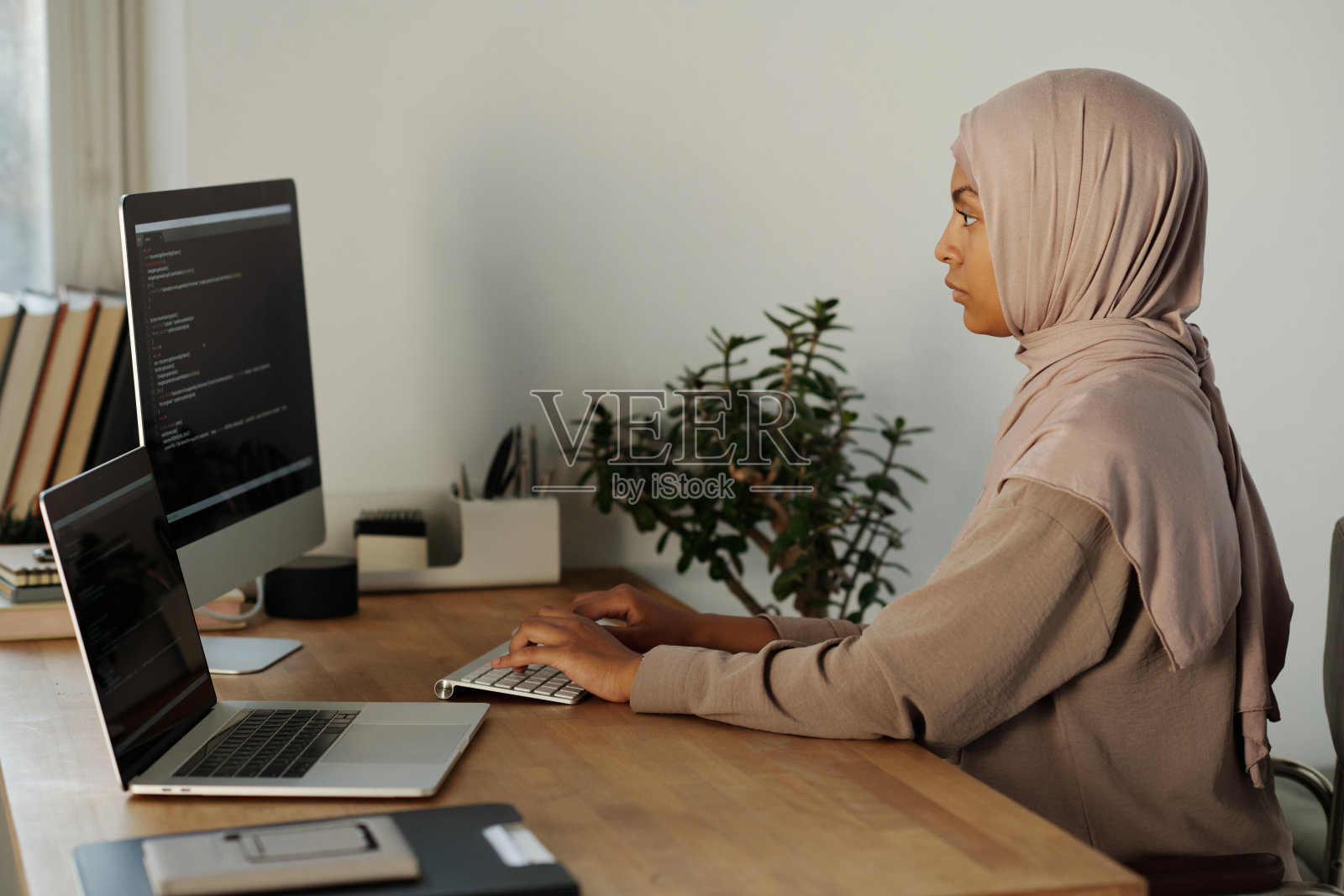 戴着头巾的年轻穆斯林女商人在电脑屏幕上解码数据照片摄影图片