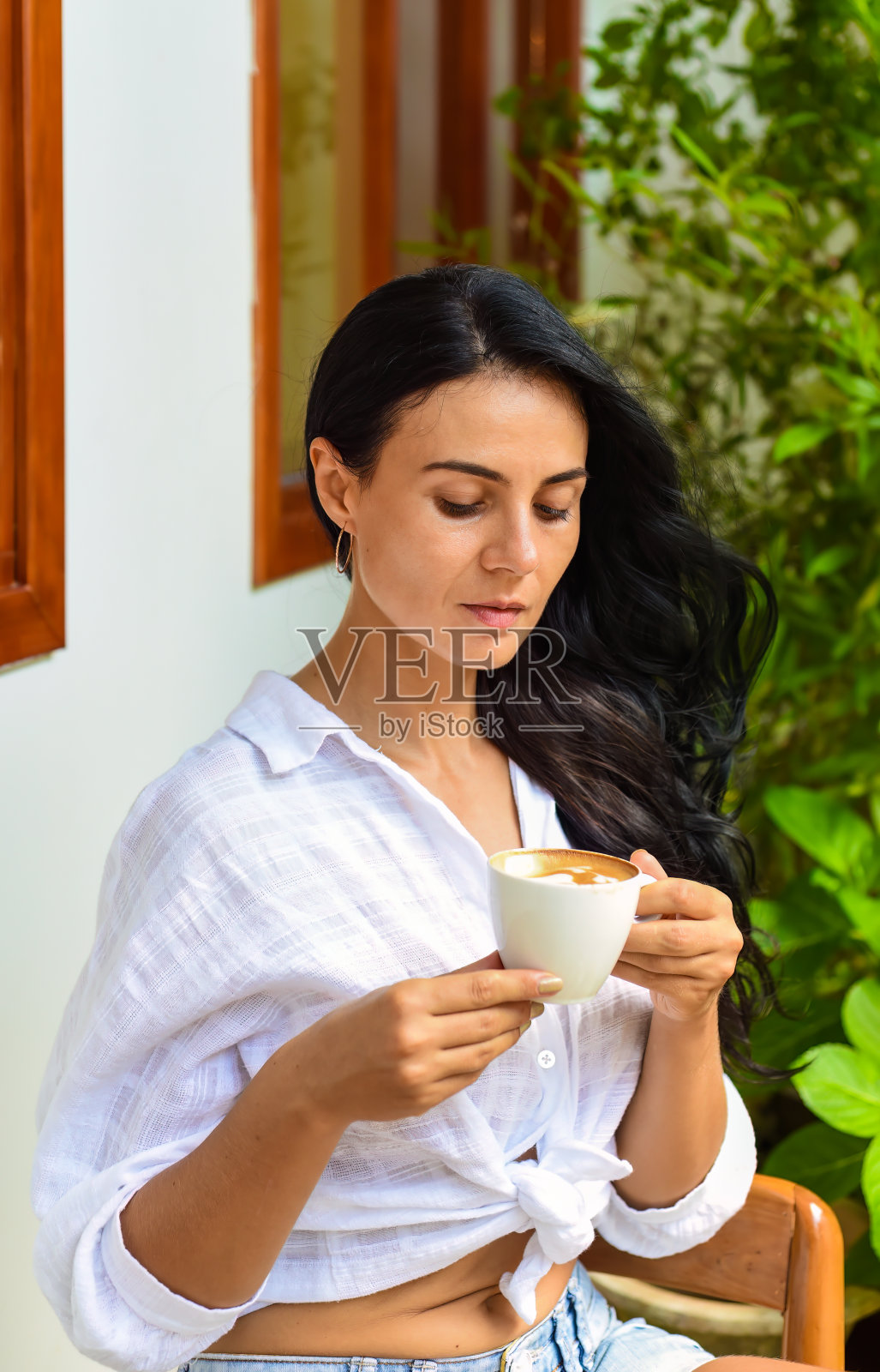 乌克兰女子微笑着喝着热卡布奇诺，看着镜头照片摄影图片