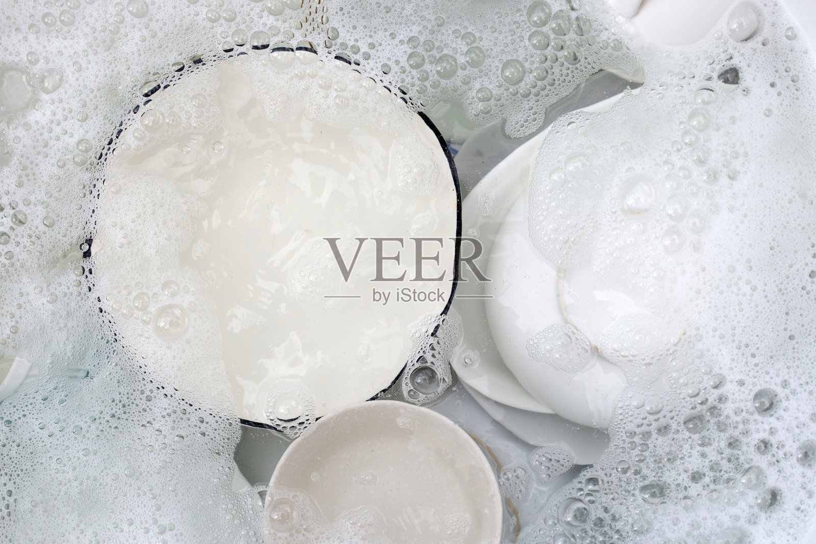 盘子和碗泡在水里和泡在洗洁精里。厨房工作照片摄影图片