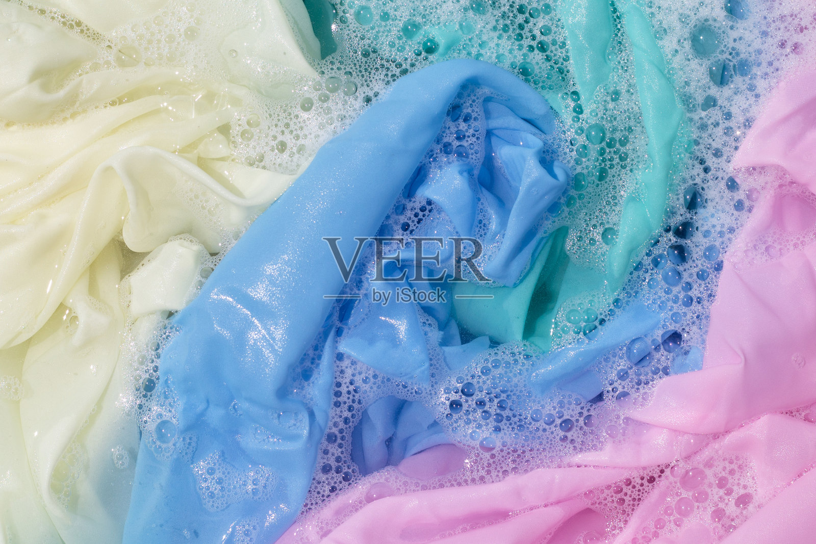 衣物浸泡在粉末洗涤剂水中溶解，洗涤有颜色的衣物照片摄影图片