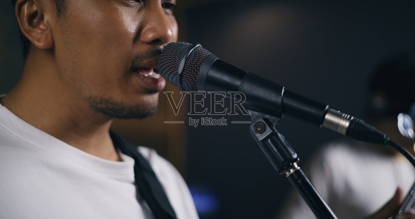 年轻的亚洲男性音乐家穿着休闲服，在歌手唱歌的同时弹着电吉他照片摄影图片